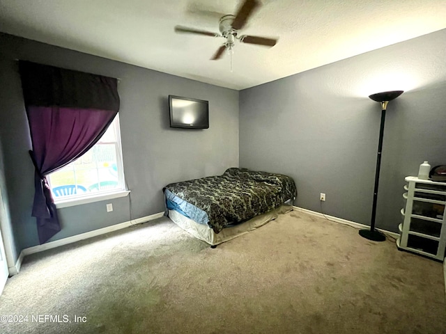 carpeted bedroom featuring ceiling fan and a textured ceiling