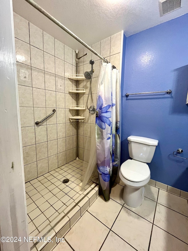 bathroom with tile patterned floors, toilet, a textured ceiling, and walk in shower