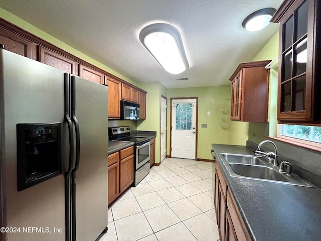 kitchen featuring light tile patterned flooring, a textured ceiling, stainless steel appliances, and sink