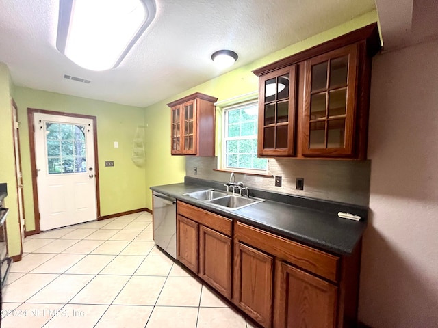 kitchen featuring stainless steel dishwasher, light tile patterned floors, sink, and a textured ceiling