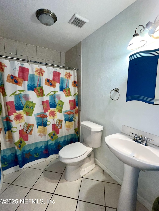 bathroom featuring tile patterned flooring, sink, curtained shower, and toilet