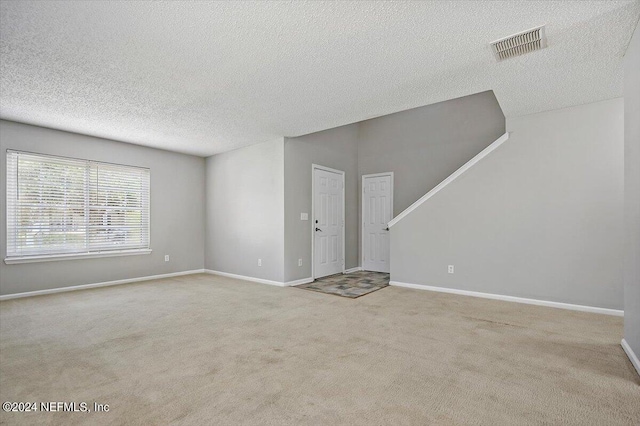 unfurnished living room with light colored carpet and a textured ceiling