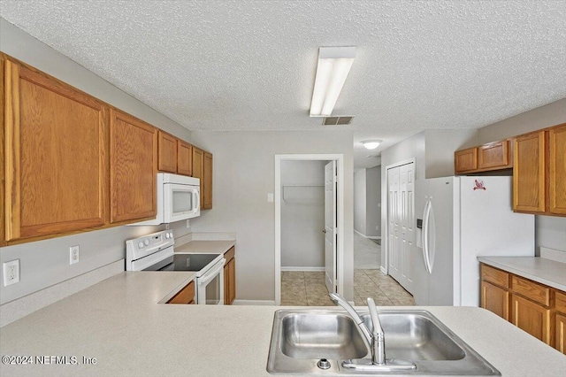 kitchen with sink, a textured ceiling, and white appliances