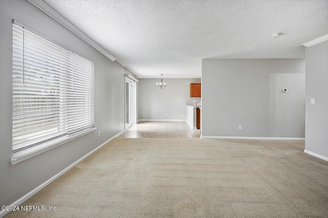 carpeted empty room featuring a notable chandelier and a textured ceiling