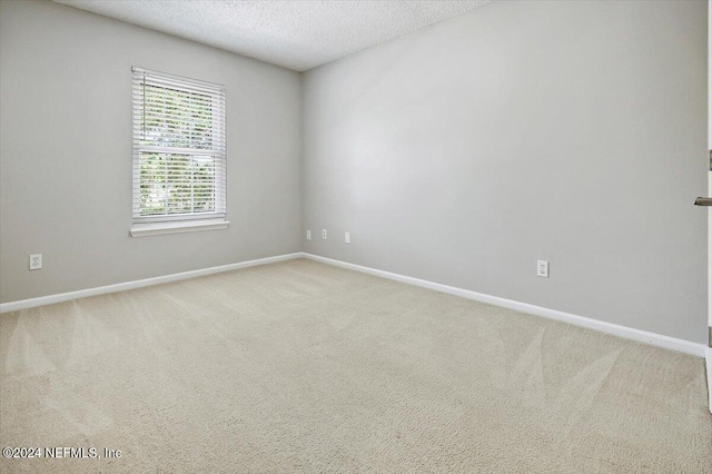 carpeted empty room featuring a textured ceiling