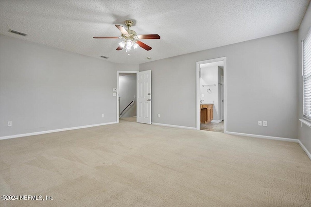 spare room with ceiling fan, light colored carpet, and a textured ceiling