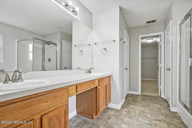 bathroom featuring vanity, an enclosed shower, and a textured ceiling