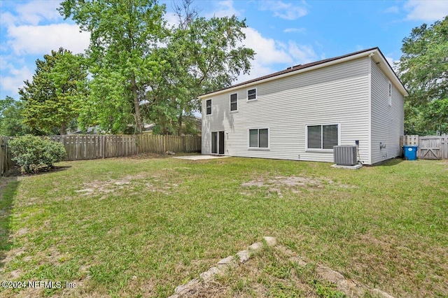 rear view of property with a yard and central air condition unit