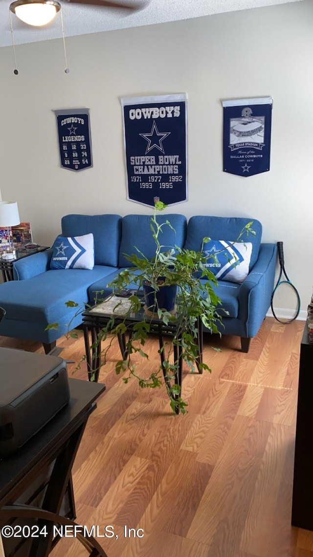 living room with light hardwood / wood-style floors, a textured ceiling, and ceiling fan