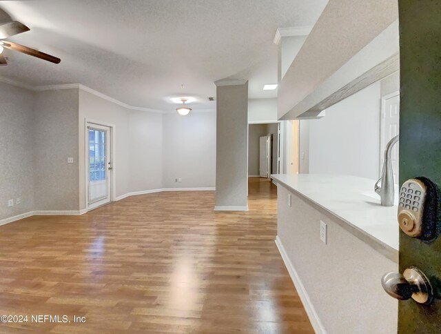 unfurnished living room with crown molding, a textured ceiling, light hardwood / wood-style flooring, and ceiling fan