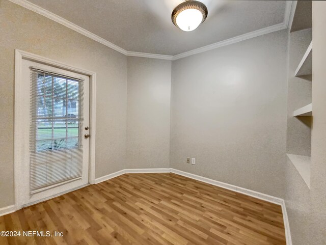 unfurnished room featuring ornamental molding and hardwood / wood-style flooring