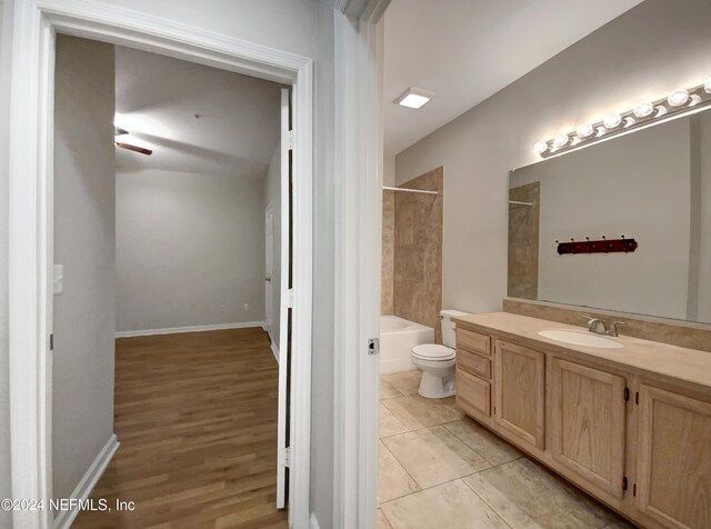 full bathroom with tile patterned flooring, tiled shower / bath combo, toilet, and vanity