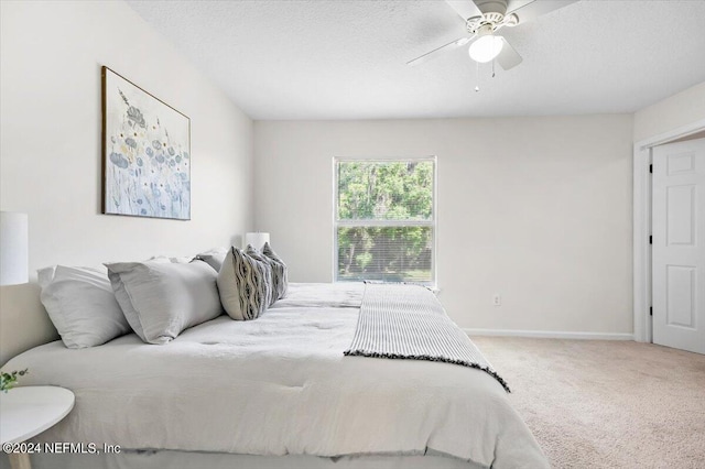 bedroom with a textured ceiling, ceiling fan, and carpet