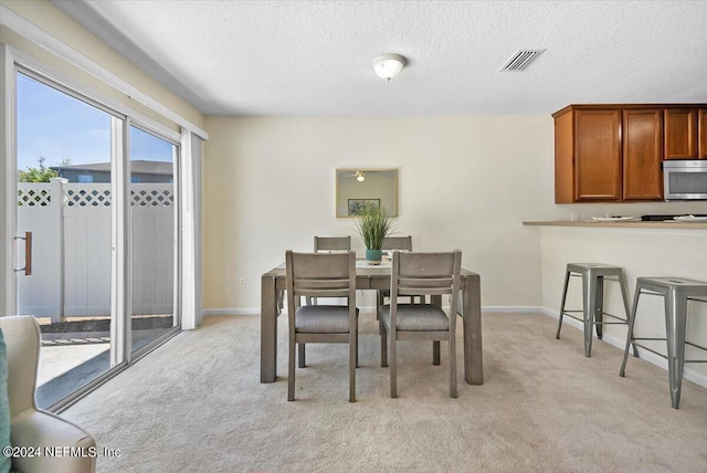 dining room featuring light colored carpet and a textured ceiling