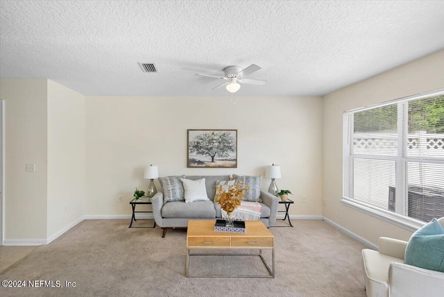 living room with light carpet, a textured ceiling, and ceiling fan