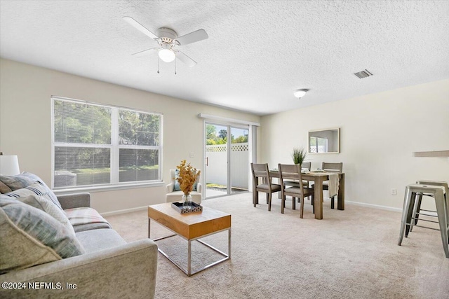 carpeted living room with ceiling fan and a textured ceiling