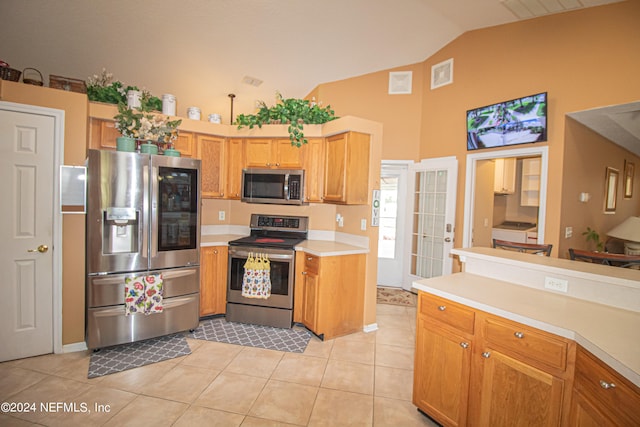 kitchen featuring light tile patterned floors, lofted ceiling, and stainless steel appliances