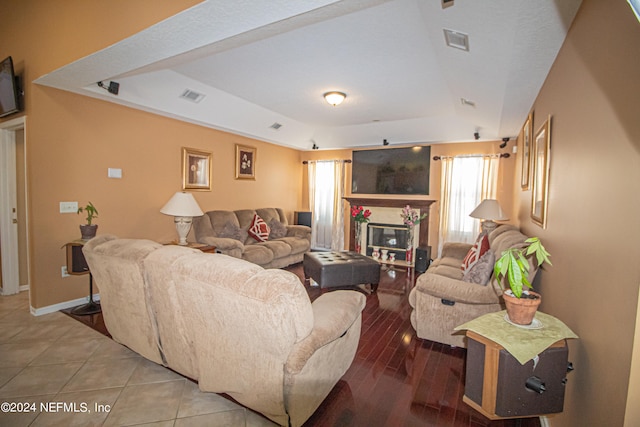 tiled living room featuring a raised ceiling and a fireplace