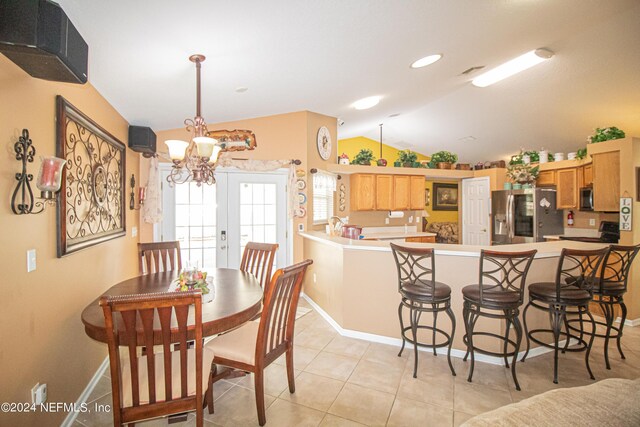 tiled dining area featuring vaulted ceiling, french doors, and a chandelier