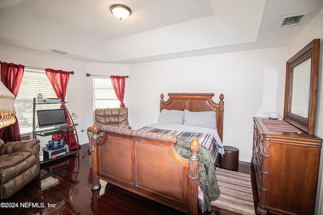 bedroom featuring dark hardwood / wood-style floors and a tray ceiling