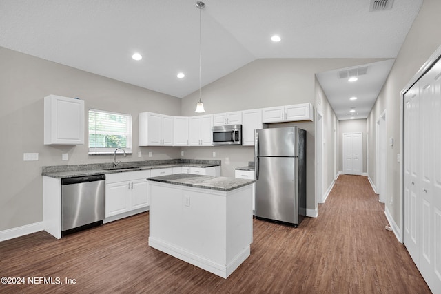 kitchen featuring visible vents, a kitchen island, hanging light fixtures, stainless steel appliances, and a sink