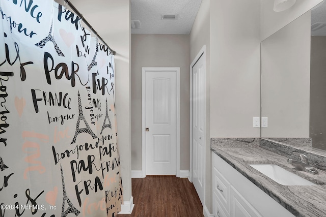 bathroom with a textured ceiling, a closet, wood finished floors, and vanity