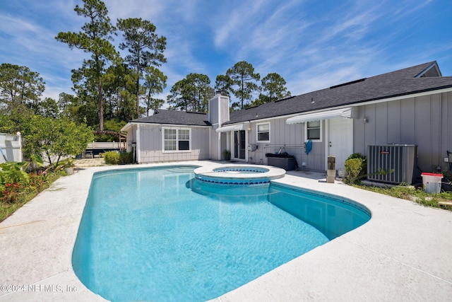 view of pool with a pool with connected hot tub, a patio, fence, and central AC unit