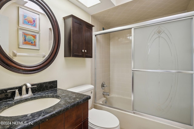 full bathroom with enclosed tub / shower combo, vanity, and toilet