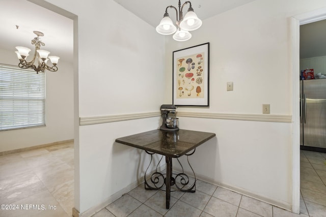 interior details featuring baseboards, freestanding refrigerator, and an inviting chandelier