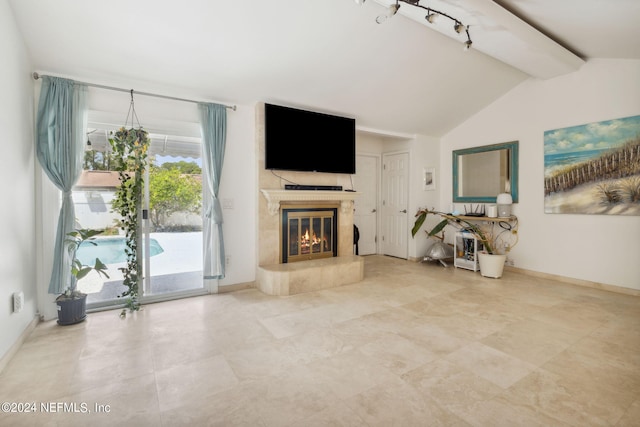 unfurnished living room featuring vaulted ceiling with beams, rail lighting, a high end fireplace, and baseboards