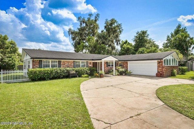 single story home with a front lawn, brick siding, fence, and an attached garage