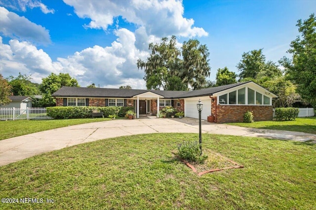 view of front facade with a garage, concrete driveway, fence, and a front lawn