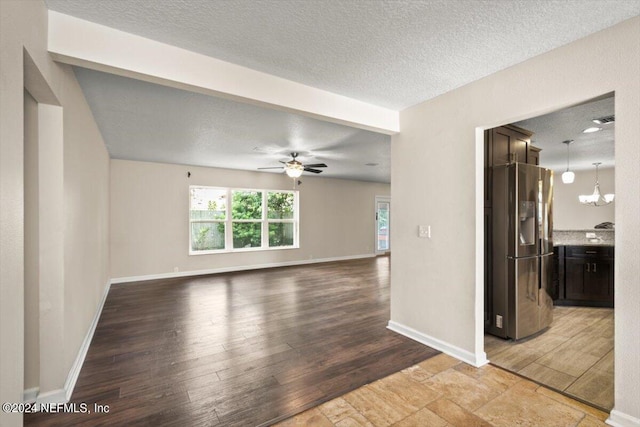 spare room with ceiling fan with notable chandelier, light hardwood / wood-style flooring, and a textured ceiling