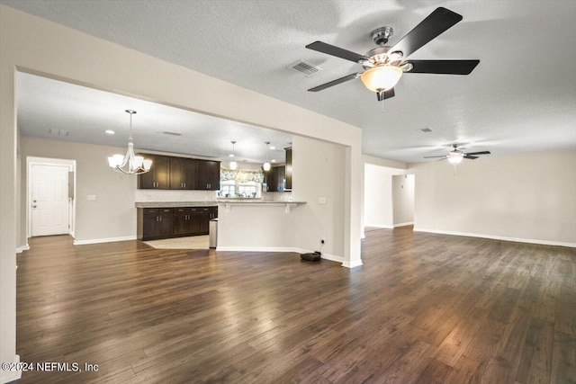 unfurnished living room featuring ceiling fan with notable chandelier, dark wood-type flooring, and a textured ceiling