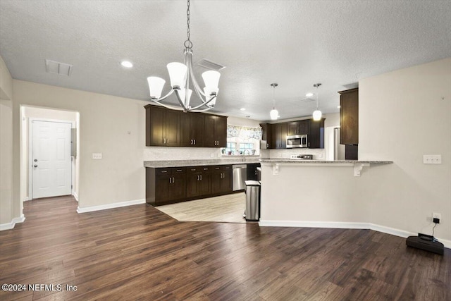 kitchen with pendant lighting, hardwood / wood-style flooring, stainless steel appliances, and kitchen peninsula