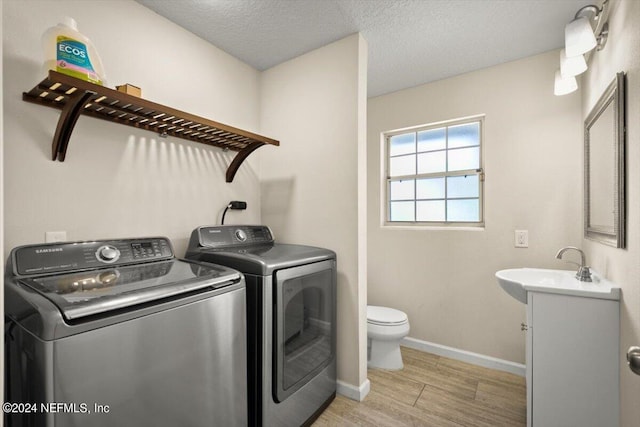 laundry area with independent washer and dryer, sink, and a textured ceiling