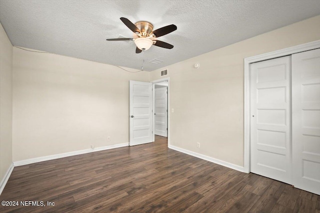 unfurnished bedroom featuring a textured ceiling, dark wood-type flooring, a closet, and ceiling fan