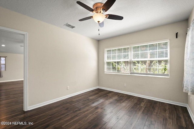 unfurnished room with ceiling fan, a healthy amount of sunlight, dark wood-type flooring, and a textured ceiling