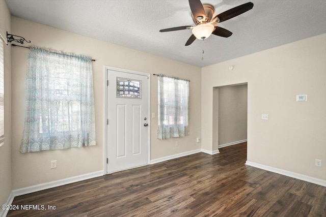 foyer entrance with ceiling fan, dark wood-type flooring, and a textured ceiling