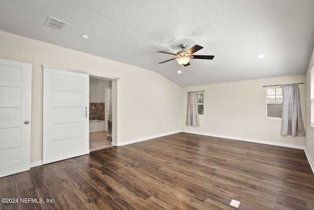 empty room with ceiling fan, vaulted ceiling, dark hardwood / wood-style floors, and a textured ceiling