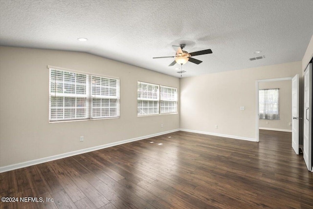 unfurnished room with lofted ceiling, plenty of natural light, dark hardwood / wood-style floors, and a textured ceiling