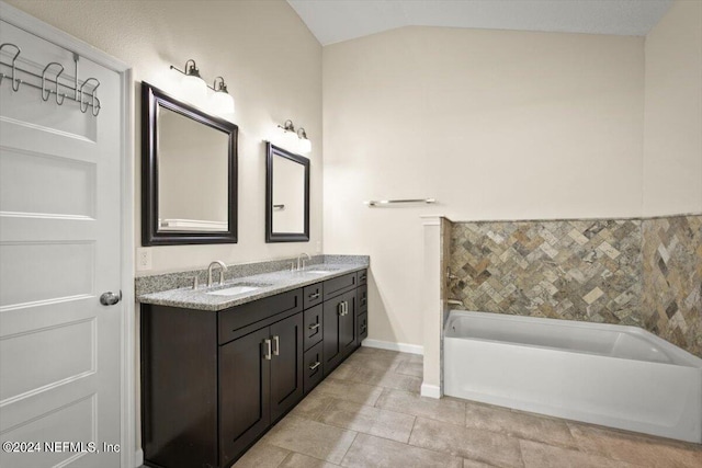 bathroom featuring lofted ceiling, a tub to relax in, vanity, and tile patterned flooring