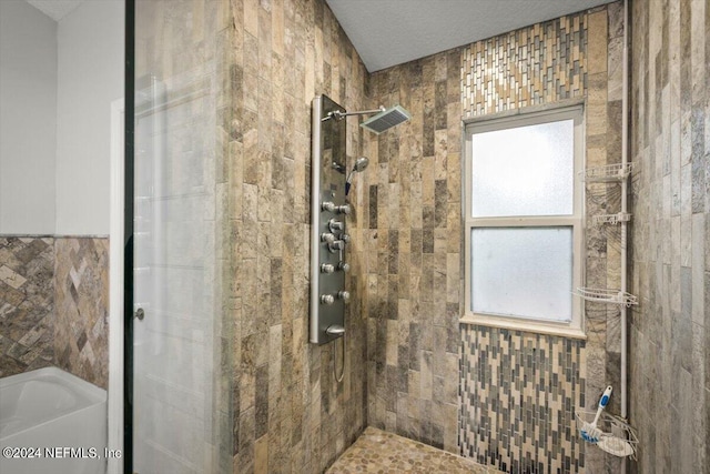 bathroom with tile walls, plus walk in shower, and a textured ceiling