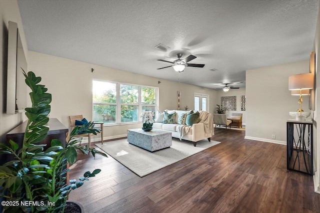 living room featuring dark wood-type flooring, ceiling fan, and a textured ceiling