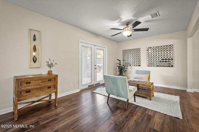 living area featuring ceiling fan, dark hardwood / wood-style floors, french doors, and a textured ceiling