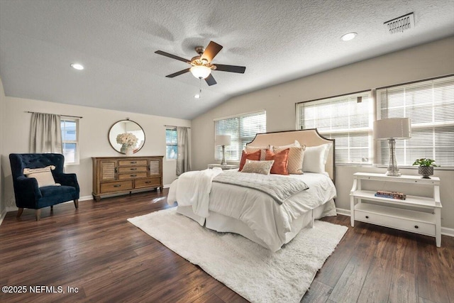 bedroom featuring ceiling fan, dark hardwood / wood-style floors, vaulted ceiling, and a textured ceiling