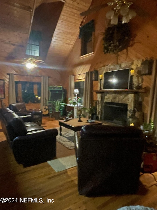 living area with high vaulted ceiling, a stone fireplace, wooden ceiling, and wood finished floors