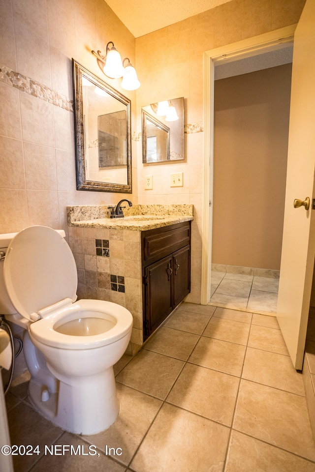 bathroom with toilet, tile patterned flooring, and tile walls