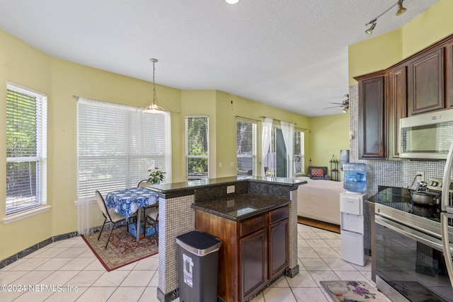 kitchen featuring dark stone countertops, appliances with stainless steel finishes, light tile patterned floors, and decorative light fixtures