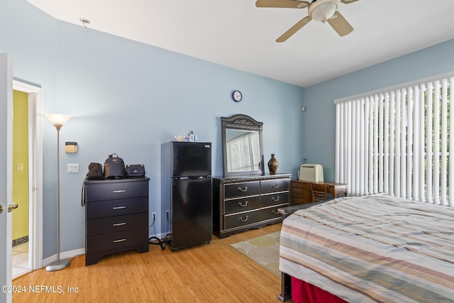 bedroom featuring black fridge, light wood-type flooring, and ceiling fan